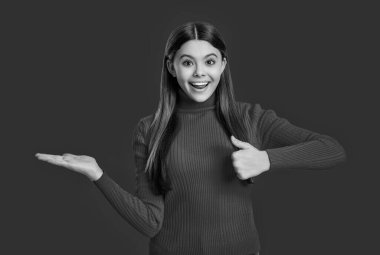 Ürünü baş parmağınla sunuyorsun. Kırmızıda izole edilmiş genç bir kızın portresi. Genç kız kameraya bakıyor. Sıradan bir tarz. Tarz sahibi kızın uzun saçları var. Genç tek renkli moda tarzında. Kız için biçim.