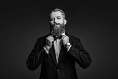 Smokin papyonlu beyefendinin lüks bir saati var. Pahalı bir kol saati. Smokinli papyonlu adam ve saat. Zarif saat aksesuarı. Zaman doldu. Gri renkte soyutlanmış zarif bir beyefendi. Erkek aksesuarı.