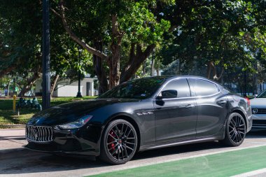 Miami, Florida, ABD - 17 Aralık 2024: Black 2014 Maserati Ghibli spor yara izi. Maserati Ghibli 'nin lüks spor arabası. Maserati Ghibli 'nin arabası dışarıda park edilmiş. Siyah Maserati Ghibli, köşe görünümü.