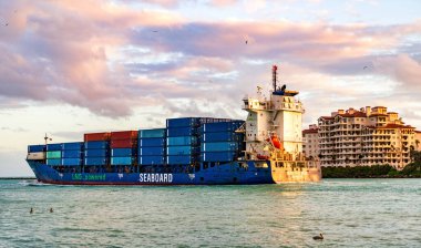 Miami, Florida, ABD - 14 Aralık 2024: Kargo Kıyısı mavi gemi hizmetleri konteynır, hava günbatımı manzaralı. Kargo gemisinde nakliye konteynırı. Kargo gemisi. Miami limanı. Konteyner gemisi.