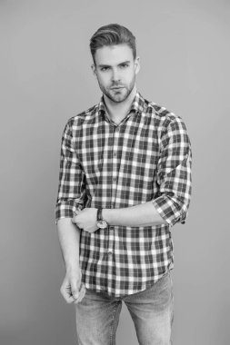 Tıraşsız adamın şık bir portresi. Gri yolda izole edilmiş bir adam. Kareli gömlek giyen milenyum adamı. Milenyum erkeğinin gündelik tarzı. Sıradan bir tişörtle genç bir adamın portresi. Kameraya bakıyorum..