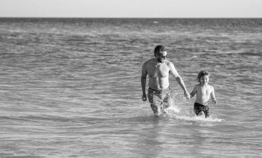 baba ve oğul deniz sahilinde koşuyorlar, kopyalama uzayı. Baba oğul, yaz tatilinin tadını çıkarıyor. Denizdeki baba ve oğul arasında özel anlar. Baba oğul maceraları. Birlikte mutlu anlar..