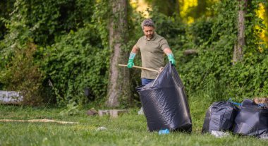 Gönüllü adam ormanda çöp topluyor. Çevresel koruma. Çevreci adam. Çevresel koruma. Çevreyi koru. Çevre plastik kirliliği, afiş.