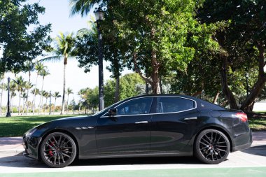 Miami, Florida, ABD - 17 Aralık 2024: Black 2014 Maserati Ghibli spor yara izi. Maserati Ghibli 'nin lüks spor arabası. Maserati Ghibli 'nin arabası dışarıda park edilmiş. Siyah Maserati Ghibli, yan görünüm.