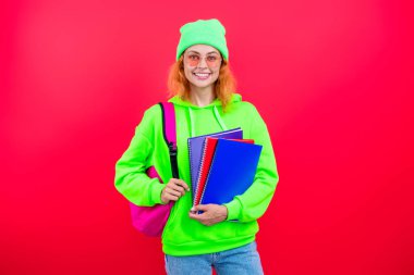 Kız öğrenci çalışma kitabını tutuyor. Okula dönelim. Bilgi toplama günü. Üniversitede eğitim. Pembe üzerine izole edilmiş bir kızın ödevi. Bilgi ve eğitim. Okul eğitimi. Modern eğitim. Bilgi güçtür..