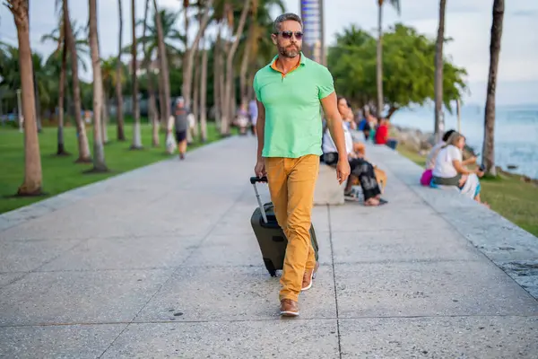 Yaz gezisi için seyahat valizleri. Yaz turu. Gezgin yaz tatili yapıyor. Şehir caddesinde yürüyen İspanyol turist. Bavullu turist. 40 'lı yılların yolcusu. Yaz tatilindeki turist.