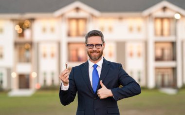 Banliyödeki emlakçı anahtarı. Yatırım amaçlı ev alan bir adam. Emlak sigortası hizmetleri. Sahibi. Amerikalı yerleşim ajanı. Emlakçı mülk satıyor. Başparmak yukarı..