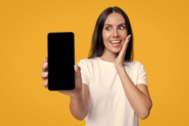 Ürünü sunuyorum. İş uygulamasının reklamı. Telefon ekranı sunan bir kadın. Sarıda izole edilmiş telefon ekranı gösteren genç bir kız. Milenyum kadını. Yeni telefon uygulaması. Kız reklam sunuyor.