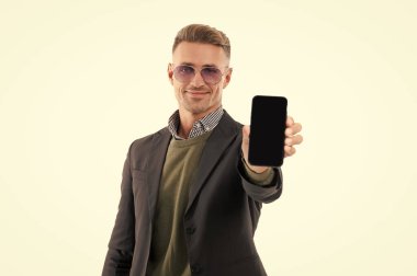 Ürünü sunuyorum. İş uygulamasının reklamı. Olgun iş adamı telefon ekranını sunuyor. İş adamı, telefonun beyazda izole olduğunu gösteriyor. Adam yeni iş telefonu uygulamasını gösteriyor. Seçici odak.