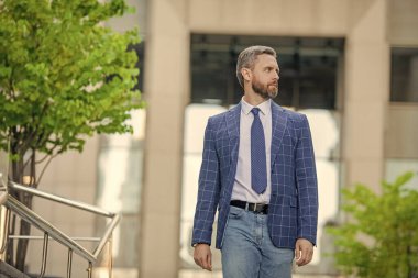 İş dünyasındaki iş adamı resmi takım elbise giyiyor ve açık havada yürüyor başarıyı ifade ediyor, kopyalama alanı.