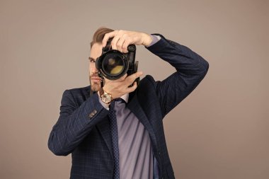 Takım elbiseli bir fotoğrafçı. Kameralı iş fotoğrafçısı. Gri renkte fotoğraf çeken gazeteci. Paparazzi fotoğrafçısı. İş adamı, fotoğraf makinesini tut. Serbest fotoğrafçı..