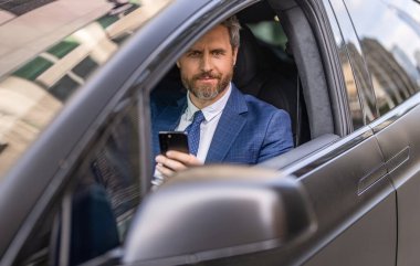 Satış. Takım elbiseli bir adam arabada telefon kullanıyor. Telefonu olan İspanyol bir işadamı. Başarılı bir bayilik. İş adamının telefonu var. Araba sigortası. Başarılı bir araba satıcısı. İş seyahati.