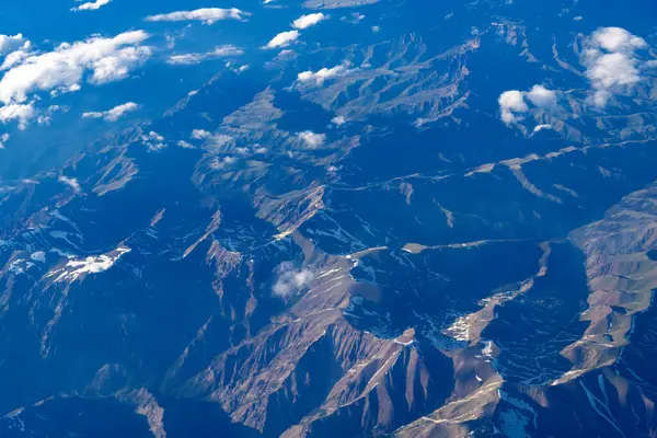 Dağ manzarasının havadan görünüşü. Hava bulutlu görünüyor. Uçaktan manzara. Dağların tepesinde, bulutların içinde. Dağlı, bulutlu bir manzara. Bulut ve dağ zirvesi hava manzarası.