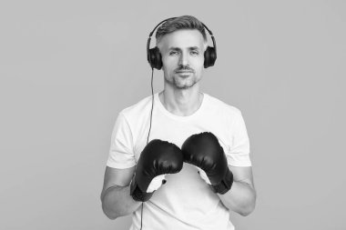 Egzersiz ve yumruk. Boks eldivenli sporcu mavi üzerine izole edilmiş. Kulaklık takan olgun bir boksör. Sporcu boks. Güçlü adam müzik dinler. Spor salonundaki sporcu. Spor giyim sektöründe boksör.