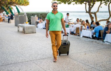 Gezgin yaz tatilinin tadını çıkar. Şehir caddesinde yürüyen İspanyol turist. Bavullu turist. 40 'lı yılların yolcusu. Yaz tatilindeki turist. Tatil gezisi için bavullar. Yaz turu.