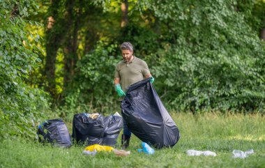 İspanyol ekoloji gönüllüsü lastik eldivenlerle çöp torbalarıyla ormanda, ekolojide çöp topluyor..