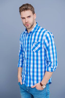 Sıradan tişörtlü bir adamın portresi. Tıraşsız adamın zarif portresi. Gri yolda izole edilmiş bir adam. Kareli gömlek giyen milenyum adamı. Milenyum erkeğinin gündelik tarzı. Temel gardırop.