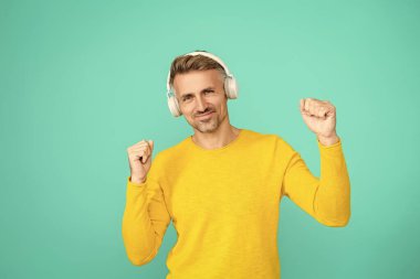 Müzik konsepti. Modern yaşam tarzı. Müzik kulaklıklarıyla ses dinleyen adam. Beyaz adam mavinin üzerinde izole edilmiş. Olgun adam sesi dinle. Olgun bir adam kulaklıkla müzik dinler. Eğleniyorum..