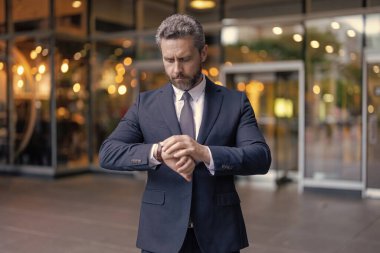 Dakik iş adamı dışarıda zamanı kontrol ediyor. İş için son gün. İş hayatına geç kalan bir iş adamı. Zaman yönetimi. Dakik adam, nöbete geç kalma zamanını kontrol ediyor. Nöbetçi iş adamı.