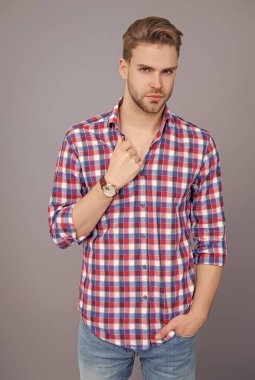 Tıraşsız yüzlü, kendine güvenen genç bir adam ve gri üzerinde izole bir saç stili..