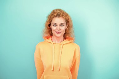 Modayla ilgilenen kız modaya uygun ve parlak görünüyor. Mavi üzerine kapüşonlu giyen kadın. Moda modeli. Şık kapüşonlu kızıl saçlı kız. Sıradan kapüşonlu, şık, beyaz bir kadın. Kapüşonlu moda.