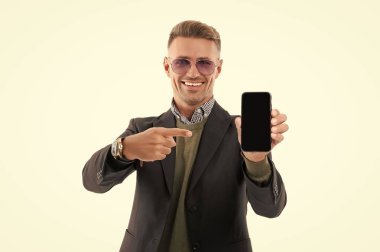 Olgun iş adamı telefon ekranını sunuyor. İş adamı, telefonun beyazda izole olduğunu gösteriyor. İşaret parmağı. Adam yeni iş telefonu uygulamasını gösteriyor. Ürünü sunuyorum. İş uygulamasının reklamı.