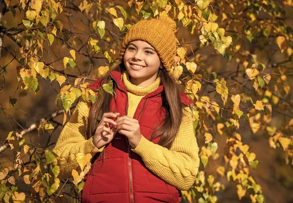Okuldaki gülen genç çocuk, güz yapraklarıyla dışarıda..