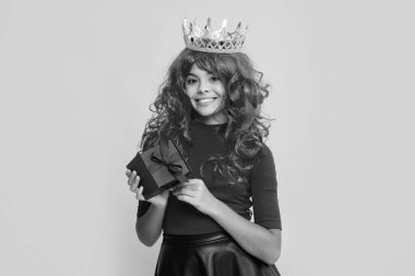 Sarı arka planda mevcut kutusuyla taç giyen pozitif çocuk.