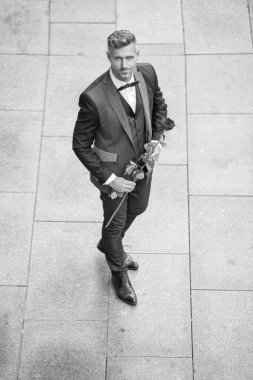 Smokinli şık bir adam. Dışarıda papyonlu takım giyen bir adam. Kırmızı güllü yakışıklı smokinli adam..