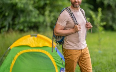 Yaz kampındaki adam. Kamp macerası. Yürüyüş konsepti. Kamp çadırı. Kampta çadır kurmuş, manzarası kesilmiş bir adam var. Yaz günü doğa yürüyüşçüsü. Yaz kampı ve doğa tatili.