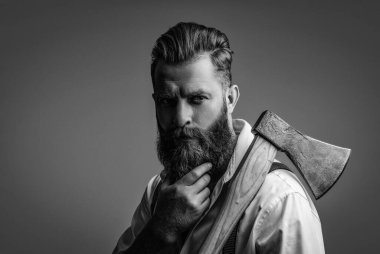 Sakallı adam, baltayı tut. Saç ve sakal bakımı. Yakışıklı, sakallı, vahşi adam. Sakal şekillendirme. Bıyıklı, Kafkas bir hippi. Sakallı adam gri yolda izole edilmiş. Klasik berber dükkanı..