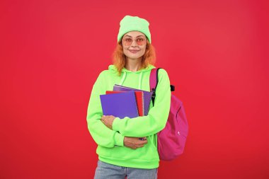 Üniversitede ya da üniversitede ev ödevi yapan genç bir kız. Pembe üzerine izole edilmiş..