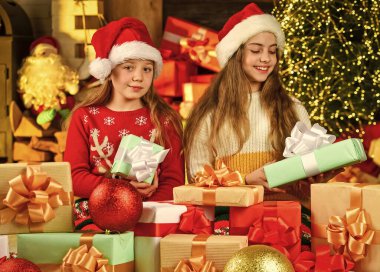 Portre seven aile. Hediyeleri olan şirin küçük kızlar. Çocuklar tatilin tadını çıkarır. Kış tatili ve tatil. Yetenekli çocuklar. Boş zaman ve eğlence. Noel hediyesi olarak Noel Baba şapkalı çocuklar.