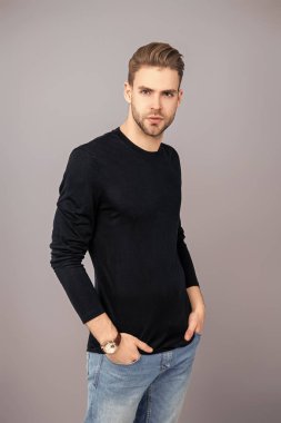 Tıraşsız yüzlü, kendine güvenen genç bir adam ve gri üzerinde izole bir saç stili..