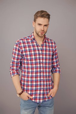 Tıraşsız yüzlü, kendine güvenen genç bir adam ve gri üzerinde izole bir saç stili..