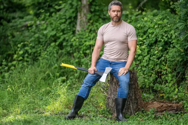 Ağaç kesen baltalı adam. Erkeksi vahşi adam. Oduncu dışarıda kamp yapıyor. Acımasız oduncu. Vahşilik ve erkeklik. Baltalı İspanyol oduncu adam. Oduncu baltası, bayrak.