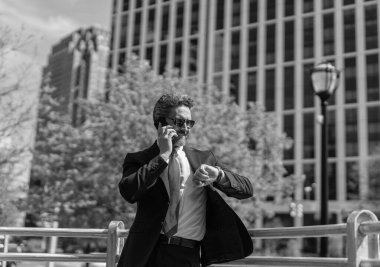 Takım elbiseli bir adam telefonda konuşuyor. Telefonu olan orta yaşlı İspanyol işadamı. İş iletişimi. İş adamının dışarıyı araması gerekiyor. İş adamı telefon kullanıyor ve saati kontrol ediyor.