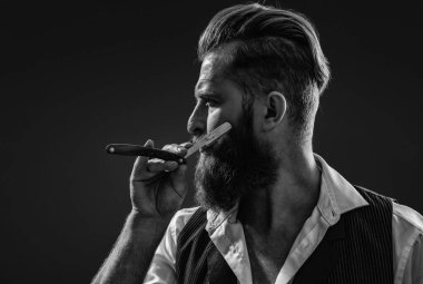 Berber retro bıçak kullanıyor. Kaba kuaför saç kesiyor. Berber dükkanında çalışan bir kuaför. Berber dükkanı. Kızıl sakallı adam. Berber dükkanındaki kuaför siyahtan soyutlanmış. Doldurulmuş sakal.