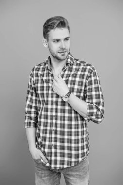 Erkek güzelliği ve saç stili. Gündelik giyinen milenyum adamı. Yakışıklı genç adam. Sıradan gömlekli bir adamın portresi. Gri üzerinde kollarını çapraz tutuyor. Tıraşsız erkek derisi. Genç model..