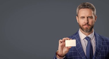 Takım elbiseli iş adamının kredi kartı Grey 'de izole edilmiş. İşletme markası. Hesabı öde. Kredi kartı olan bir iş adamı. Emoney ile iş anlaşması. İş başarısı. Uzayı kopyala Şirket logosu.