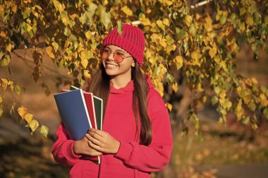 Sonbahar ders çalışma zamanıdır. Bilgi ve eğitim. Okul bilgisi. Okula dönüyorum. Sonbahar kızı okul ödevini tutuyor. Ergenlik bilgisi. Sonbahar parkındaki genç kız. Erken eğitim.