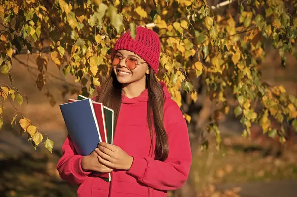 Sonbahar ders çalışma zamanıdır. Bilgi ve eğitim. Okul bilgisi. Okula dönüyorum. Sonbahar kızı okul ödevini tutuyor. Ergenlik bilgisi. Sonbahar parkındaki genç kız. Erken eğitim.