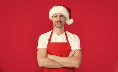 Kırmızı kahve önlüklü ve Noel Baba şapkalı olgun bir adam..