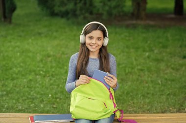 Okula dönelim. Eğitim ve bilgi. Kitapla sesli kitap dinleyen kız. Audiobook ödevi. Öğrenci kız. Okul eğitimi. Öğrenci hayatı. Liseli kız dışarıda kulaklıkla müzik dinliyor..
