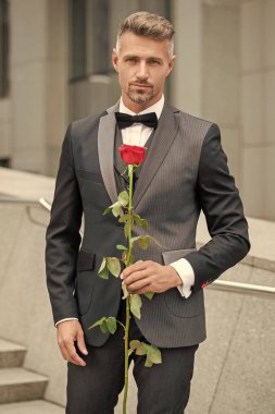 Siyah smokinli zarif bir adam. Smokin papyon takan adam dışarıda. Kırmızı güllü şık smokinli adam..