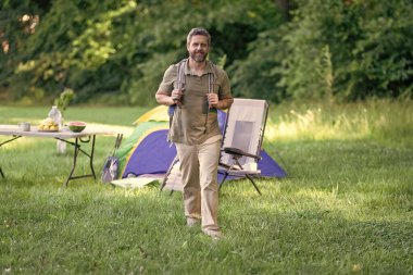 Ormanda çadırda çadırda bir adam var. Bir yaz günü doğa yürüyüşçüsü. Yaz kampı ve doğa tatili. Yaz kampındaki adam. Kamp macerası. Yürüyüş konsepti. Kamp çadırı. Doğa kaçamağı.