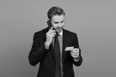 Çevrimiçi bankacılığa telefon. Kredi kartı ya da banka kartı. Telefonda konuşan iş adamı Grey 'de izole edilmiş. İş adamı telefon görüşmesi için kartı kullanır. İş iletişimi devrede. Kartvizit. Benimle temasa geç..