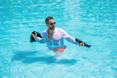 Başarılı, ıslak, serbest çalışan. İş seyahati başarılı. İş gezisi. Yaz tatilindeki mutlu iş adamı. Freelancer 'ın uzaktan kumandası var. Takım elbiseli bir işadamı havuzda dinleniyor..