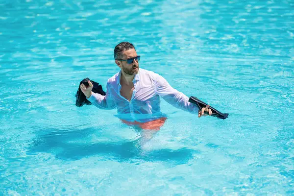 Başarılı, ıslak, serbest çalışan. İş seyahati başarılı. İş gezisi. Yaz tatilindeki mutlu iş adamı. Freelancer 'ın uzaktan kumandası var. Takım elbiseli bir işadamı havuzda dinleniyor..