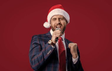 Noel 'de şarkı söyleyen adamın kırmızı ışıkta izole olmasına sevindim. Noel etkinliği sunucusu şarkı söylüyor. Noel Baba şapkasıyla şarkı söyleyen bir sunucu. Etkinlik sunucusu mikrofonla şarkı söylüyor. Mutlu Noeller..